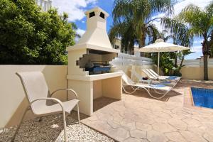 a outdoor kitchen with two chairs and an umbrella at Nissi Sapphire Villa in Ayia Napa