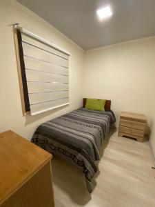 Habitación pequeña con cama y ventana en Hostal Entre Los Lagos en Villarrica