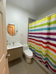 y baño con aseo y cortina de ducha de arco iris. en Hostal Entre Los Lagos en Villarrica