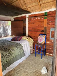 ein Schlafzimmer mit einem Bett und einem Stuhl in einer Hütte in der Unterkunft Near Lake Hostal in Bacalar