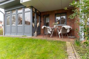 Cette maison dispose d'une terrasse avec une table et des chaises. dans l'établissement Koje 34, à Sankt Peter-Ording