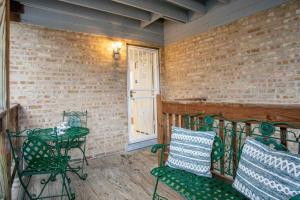 a porch with green chairs and a table and a brick wall at Chicago Charm in Chicago