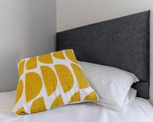 uma cama com uma almofada amarela e branca em The Doneraile Room 2 em Waterford