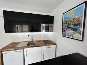 a kitchen with white cabinets and a sink and a picture at Magnifique studio au bord de mer in Nice