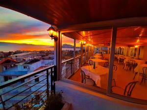 a balcony with tables and chairs and a sunset at Mitho Hotel Spa in Loutra Edipsou