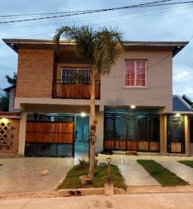 a house with a palm tree in front of it at Departamento Aires del Golf in Termas de Río Hondo