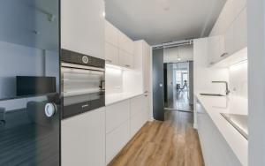 a kitchen with white cabinets and a wooden floor at K129 Living Apartment in Vilnius Center in Vilnius