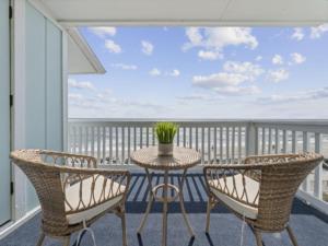 a table and chairs on a balcony with a view of the ocean at A Little Shore Thing condo in Carolina Beach