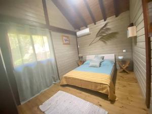 una camera con un letto in una stanza con pavimenti in legno di Bungalow Ti Zaboka a Les Abymes