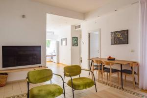 a living room with a television and a table and chairs at Renovated 2BR with Balcony in Bauhaus *Beachfront* in Tel Aviv