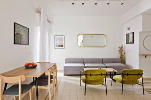 a living room with a couch and a table and chairs at Renovated 2BR with Balcony in Bauhaus *Beachfront* in Tel Aviv