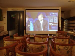 una pantalla de proyección en una habitación con un grupo de sillas en Hotel Excelsior en Cervia