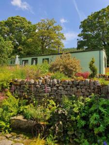 a garden with a stone wall and a green building at Howgill farm Bolton Abbey in Appletreewick