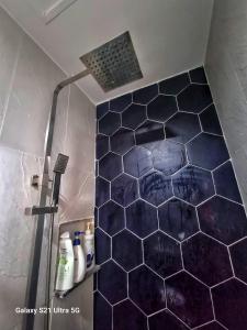 uma casa de banho com um chuveiro e piso em azulejo azul em Luxurious Romantic Getaway in a stylish Condo em Tagaytay