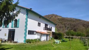 un edificio blanco con adornos verdes y una montaña en Apartamentos Florinda, en Ucieda de Abajo