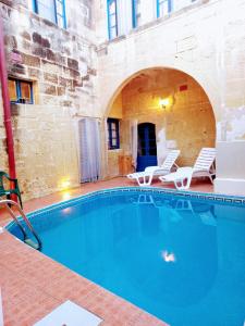 a large swimming pool in a building with two chairs at Ta lucia farmhouse with private pool and BBQ in Santa Luċija