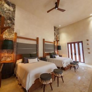 a bedroom with two beds and a stone wall at Oriundo Luxury Nature Villas in Valladolid