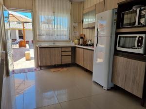 een keuken met een witte koelkast en een magnetron bij Casa Marfim - Piscina - Mariscal in Canto Grande