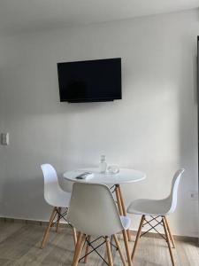 a white table and chairs with a television on a wall at Enastron Cozy & Quiet Apartment in Heraklio