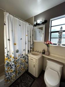 Un baño con inodoro, lavabo y cortina de ducha. en Beach Break House by the Surf, en Daytona Beach