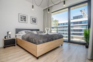 a bedroom with a bed and a large window at Apartamenty Shellter Rogowo - ALL DAY HOLIDAY in Rogowo