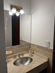 a bathroom with a sink and a large mirror at Uptown City Apart La Falda in La Falda