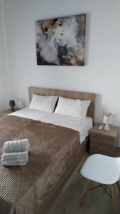 a bedroom with a bed and a white chair at Iliaktis Cozy & Quiet Apartment in Heraklio Town