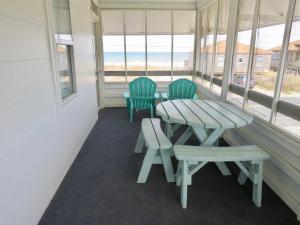 um alpendre com uma mesa, 2 cadeiras e uma janela em Saltaire Cottages em Kitty Hawk Beach