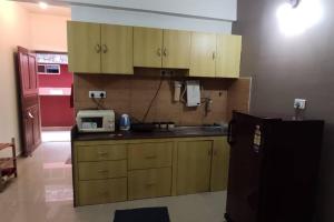 a kitchen with wooden cabinets and a microwave and a refrigerator at Furnished Apt near Palolem Beach¶WiFi ¶Forest view in Canacona