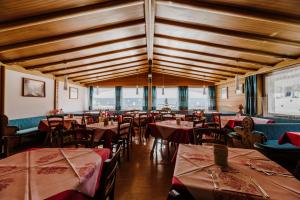 comedor con mesas y sillas y techos de madera en Hotel Rosa Wellness & SPA, en Vigo di Fassa