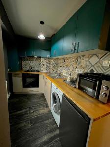 a kitchen with green cabinets and a washing machine at Studio G1 in Moineşti