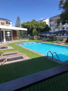 a large swimming pool with a green lawn around it at Luxury one bedroom apartment in Somerset West