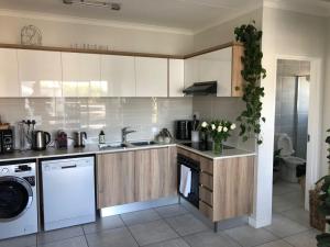 a kitchen with white cabinets and a sink and a dishwasher at Luxury one bedroom apartment in Somerset West