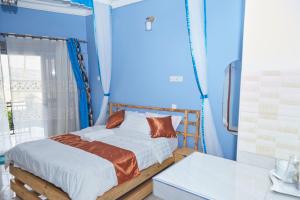 Cama en habitación con pared azul en WestWay Luxury Suites, en Mbarara