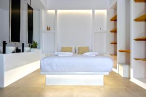 um quarto branco com uma cama branca e prateleiras em Oliva Naxos Apartments em Naxos Chora