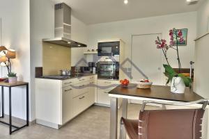 eine Küche mit weißen Schränken und einem Tisch mit Stühlen in der Unterkunft LocaLise - M11 - Ty Gwennili - Maison de plain pied avec terrain entièrement clôturé - Accès plage et centre à pied - Wifi inclus - Draps inclus - Animaux non admis in Le Guilvinec