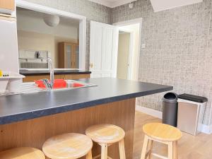 cocina con fregadero y taburetes de madera en Shirley House 4, Guest House, Self Catering, Self Check in with smart locks, use of Fully Equipped Kitchen, close to City Centre, Ideal for Longer Stays, Excellent Transport Links en Southampton