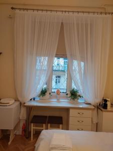 een slaapkamer met een bureau en een raam met gordijnen bij Zati Suite in Boedapest