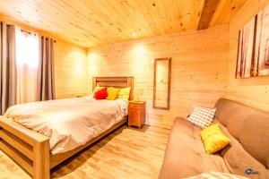 ein Schlafzimmer mit einem Bett und einem Sofa in einem Zimmer in der Unterkunft Chalet bois rond aux paysages uniques avec Spa ! in Lac-aux-Sables