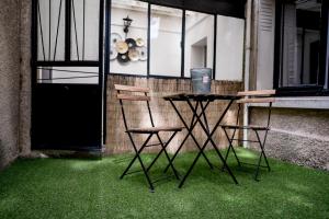 two chairs and a table on a patio with green grass at Le Patio, Climatisation Terrasse Wi-Fi Netflix 15 mn coeur de ville in Béziers