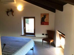 ein Schlafzimmer mit einem Bett, einem Fenster und einem Stuhl in der Unterkunft Casa Torre con terrazza panoramica in Futani