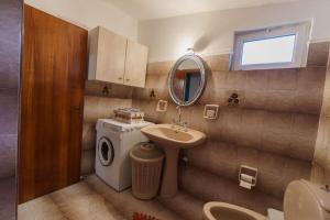 een badkamer met een wastafel en een wasmachine bij Tsigkos Apartment ! in Áno Dholoí