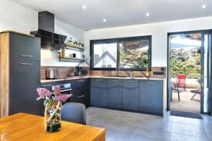 eine Küche mit blauen Schränken und einem Holztisch in der Unterkunft LocaLise - M68 - An Aod Melen - Maison neuve à 50m de la plage et à quelques pas du centre et des plages - Draps inclus - Wifi inclus in Le Guilvinec