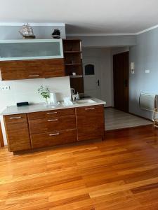 a kitchen with wooden cabinets and a wooden floor at Apartament przy promenadzie Mikolajki. in Mikołajki