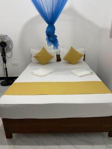 łóżko z żółtą i niebieską pościelą i poduszkami w obiekcie The Pearl w mieście Marawila