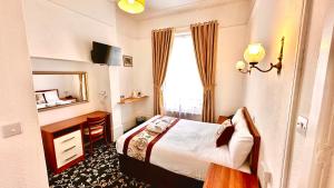 a bedroom with a bed and a desk and a window at Andorra Guest Accommodation in Brighton & Hove