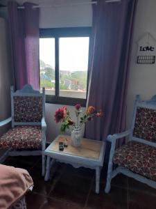 a room with two chairs and a table with flowers on it at Mi Placer in Valverde