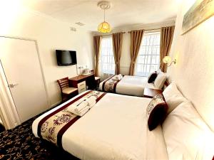 a hotel room with two beds and a television at Andorra Guest Accommodation in Brighton & Hove