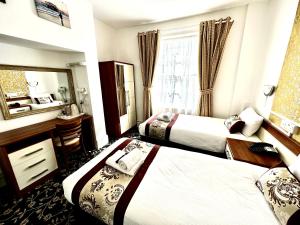 a hotel room with two beds and a mirror at Andorra Guest Accommodation in Brighton & Hove