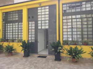 Residence Jolly في ميلانو: مبنى أصفر أمامه نباتات خزف